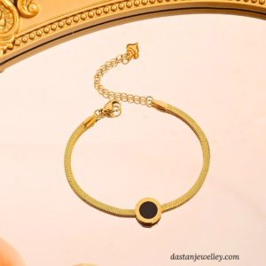 Close-up of black dial charm on golden stainless steel bracelet