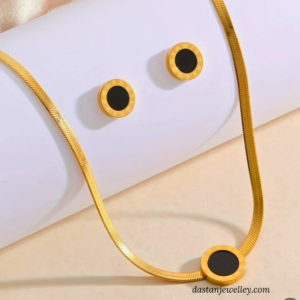 Close-up of matching black dial ear studs with gold rim detail