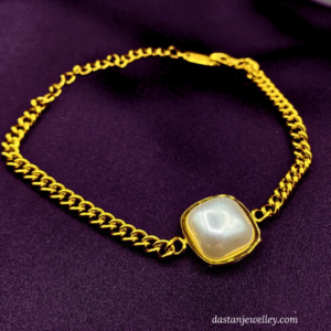 Close-up of white pearl centre on golden stainless steel bracelet