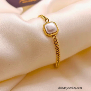 Flatlay showing bracelet with pearl centre and rich gold tone